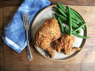 A plate with crunchy cried chicken and green beans with a fork and a blue napkin