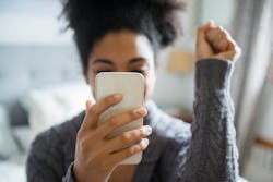 A young woman with a ponytail holding a phone in front of her face