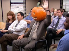 Dwight Schrute sits in the conference room during a Halloween episode of 'The Office' with a pumpkin...
