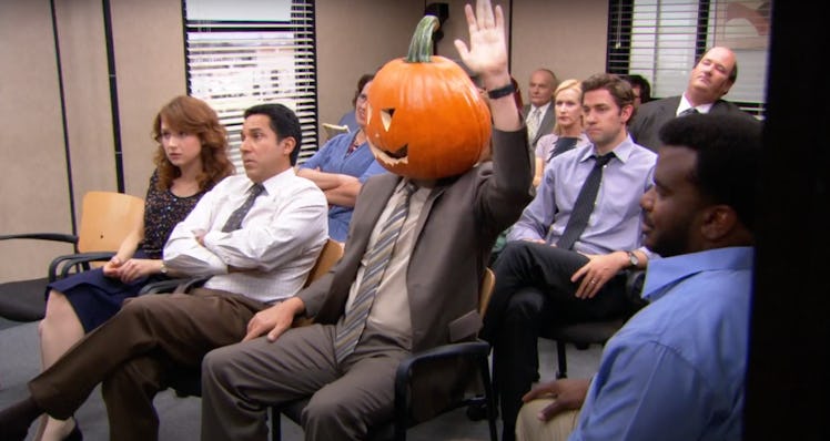Dwight Schrute sits in the conference room during a Halloween episode of 'The Office' with a pumpkin...