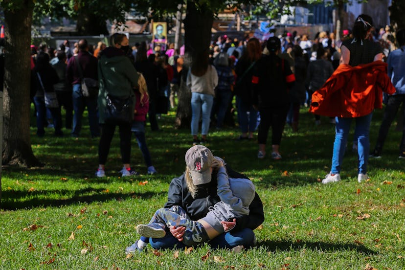 A mother and her child take a break on the grass at the Boston Women's March in October. 