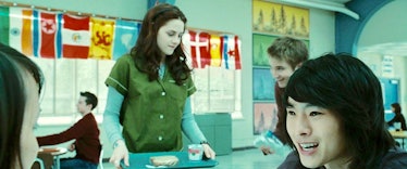 Bella walks into the cafeteria holding a tray of food to sit with Angela, Eric, and Mike. 
