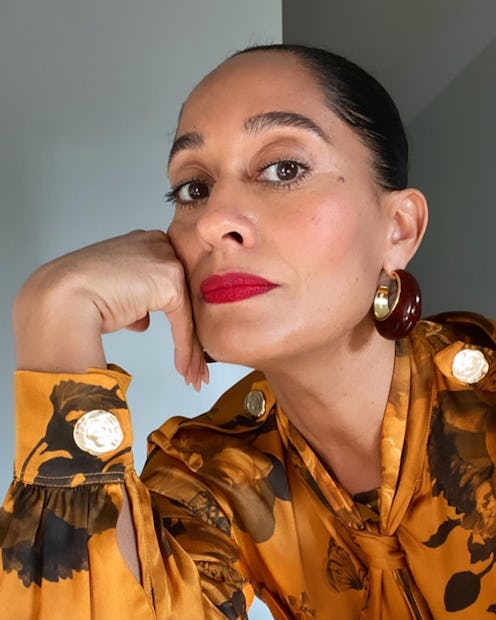 Tracee Ellis Ross posing with red lipstick, and an orange floral button up shirt