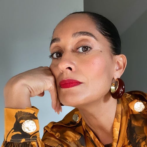 Tracee Ellis Ross posing with red lipstick, and an orange floral button up shirt