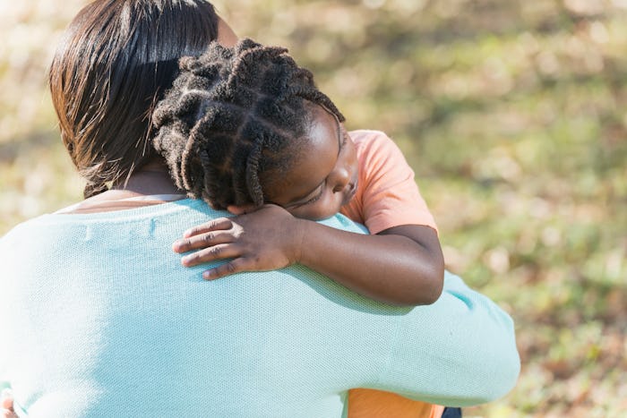 Close up of an African American mother hugging her 4 year old son. His eyes are closed and he has a ...