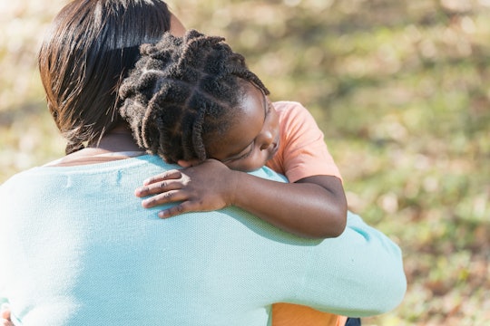 Close up of an African American mother hugging her 4 year old son. His eyes are closed and he has a ...