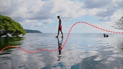 A man walking on an edge of an infinity pool during his Thailand honeymoon