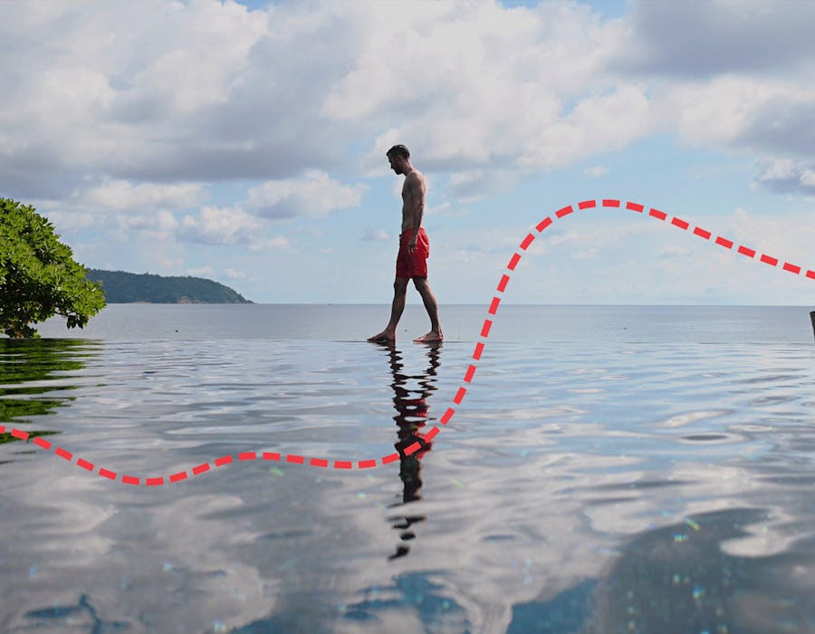 A man walking on an edge of an infinity pool during his Thailand honeymoon