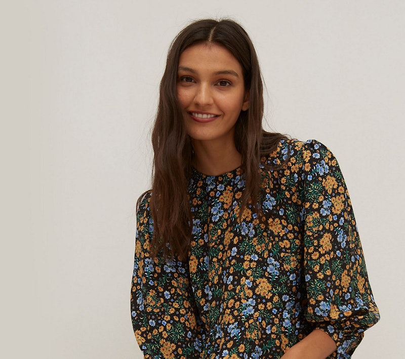 A model wearing a black, blue green and mustard floral dress