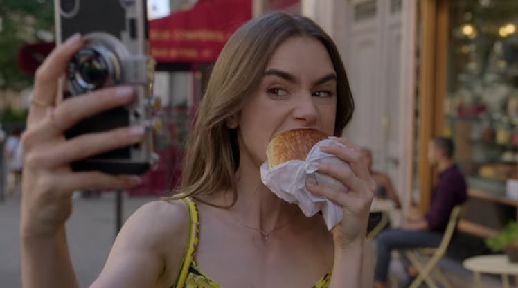 Emily (Lily Collins) takes a big bite of a chocolate croissant. 
