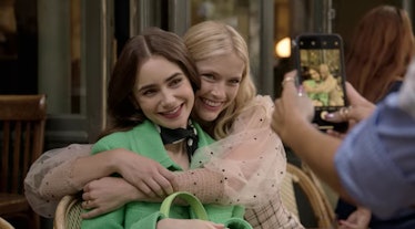 Emily (Lily Collins) and Camille (Camille Razat) hug each other for a picture, while sitting in a ca...