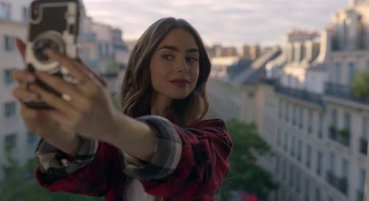 Emily (Lily Collins) takes a selfie while standing in front of her apartment window. 