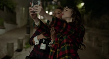 Emily (Lily Collins) and Mindy (Ashley Park) take a selfie on a street in Paris at night. 
