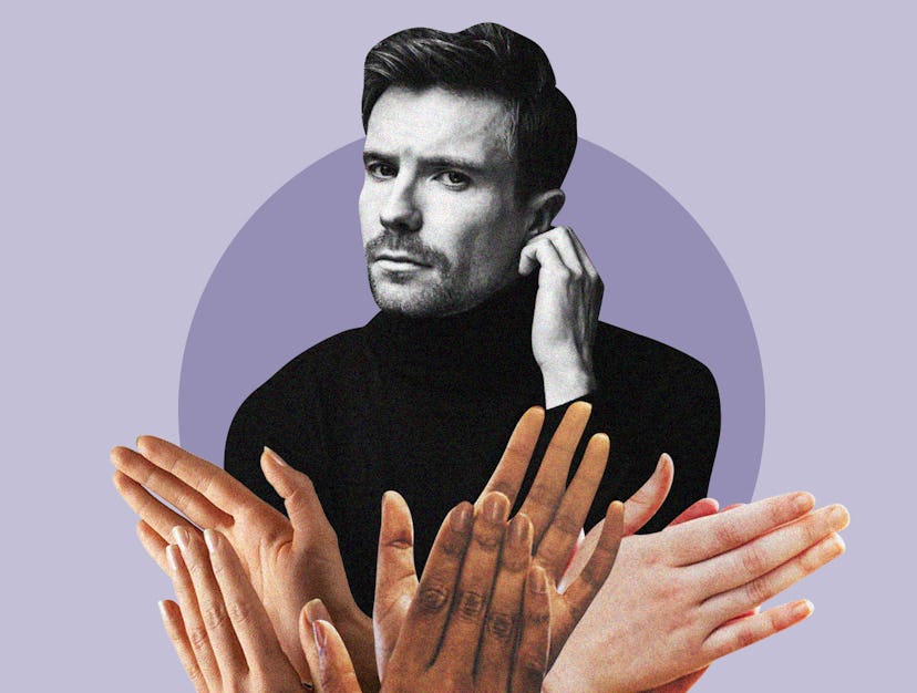 Joe Dempsie posing in a black turtleneck while a group of hands clap in front of him