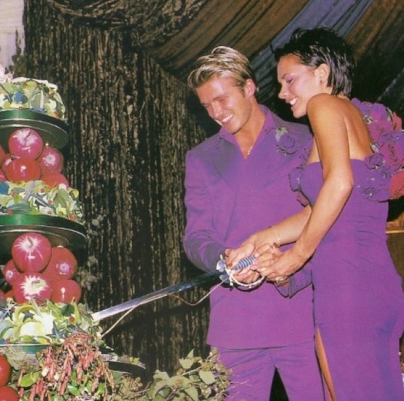 David and Victoria Beckham dressed in royal purple outfits cutting their wedding cake