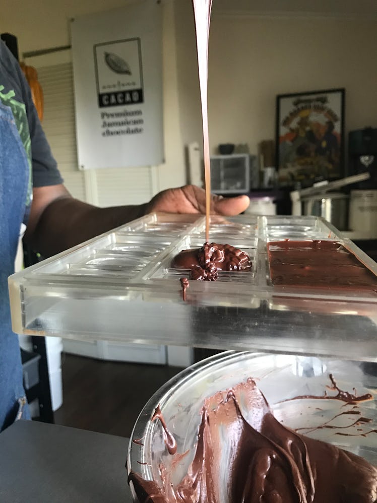 A chocolate maker pours melted chocolate into molds.