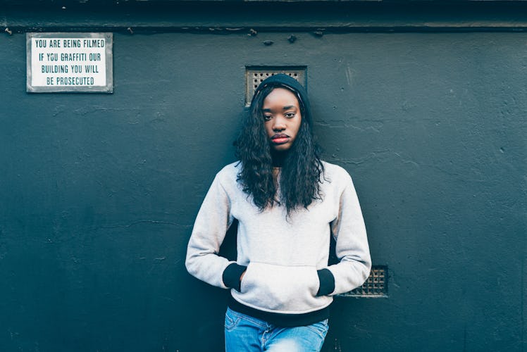 Black woman standing near the wall with warning sign