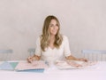 Lauren Conrad sits at a table with some fabric and pattern swatches. 