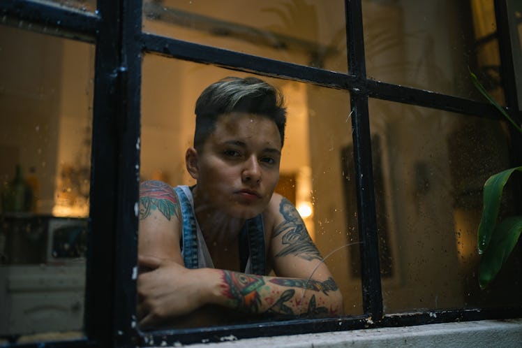 Young woman with tattoos looking out window