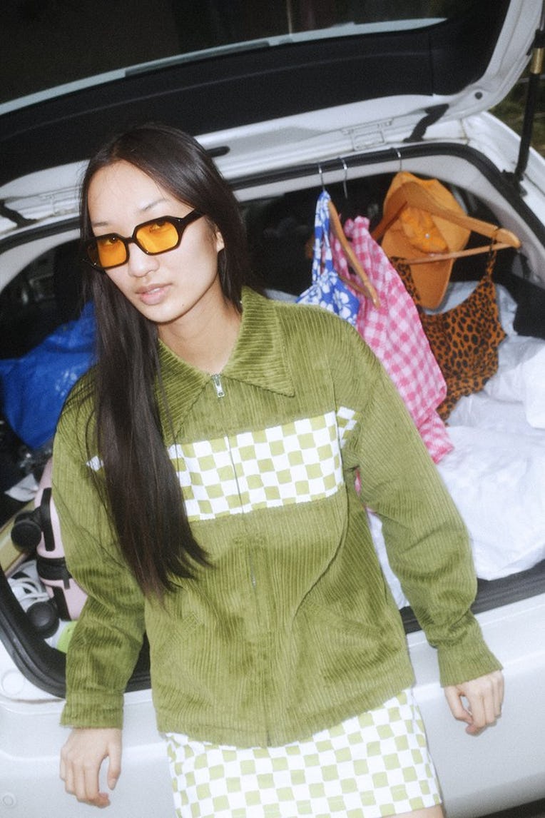 Asian woman wearing an olive sweater and yellow-tinted glasses 