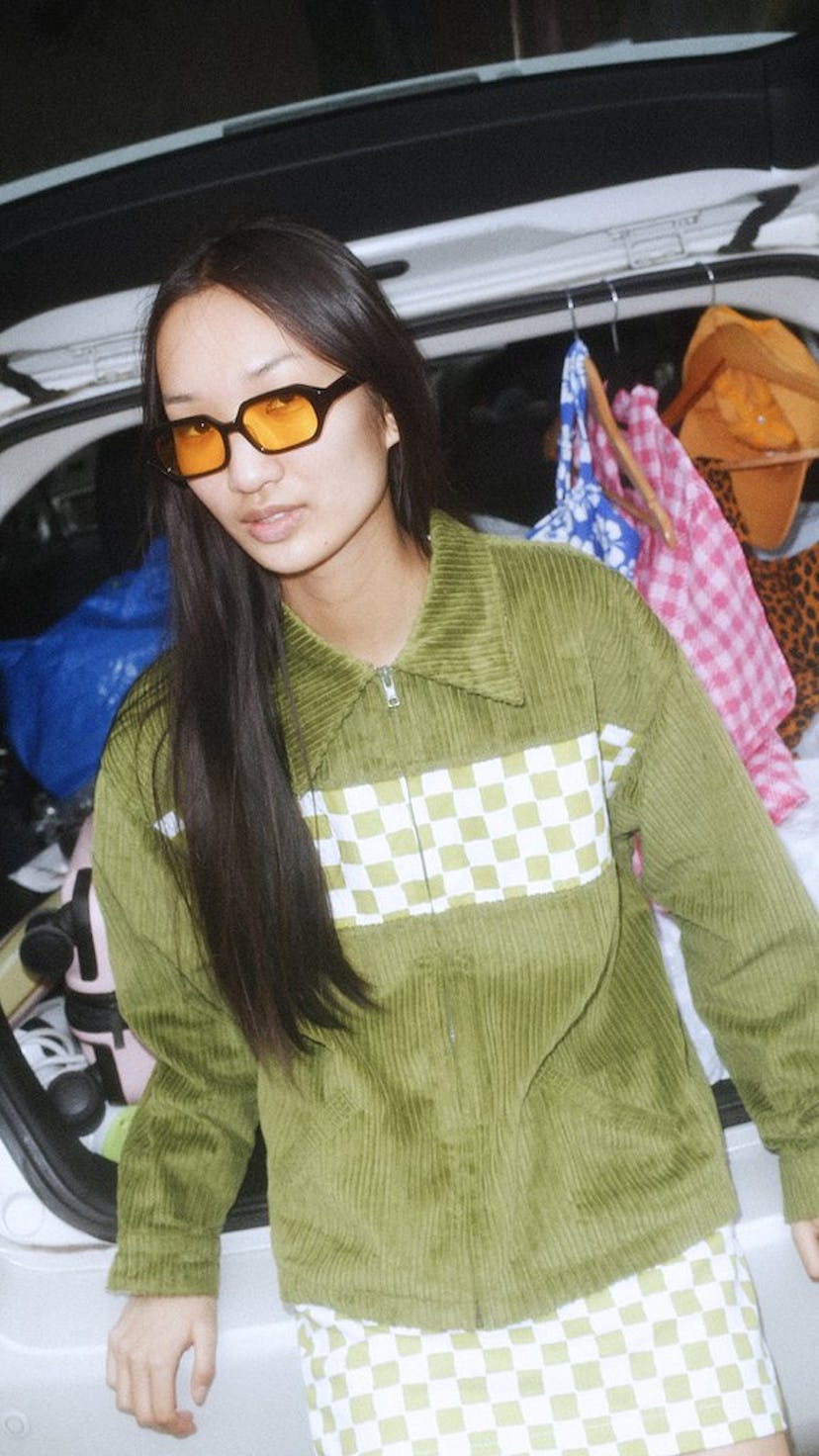 Asian woman wearing an olive sweater and yellow-tinted glasses