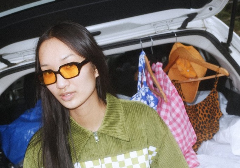Asian woman wearing an olive sweater and yellow-tinted glasses 