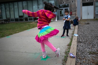 A little girl twirls around on the sidewalk outside her school, during a "mask break" from Kindergar...