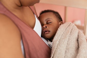 A beautiful Black baby sleeps snuggled up on his mama's chest.