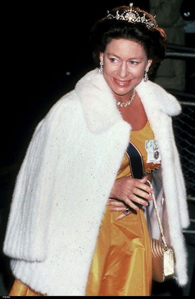 Princess Margaret wearing a white fur coat over a yellow satin gown and a crown, smiling