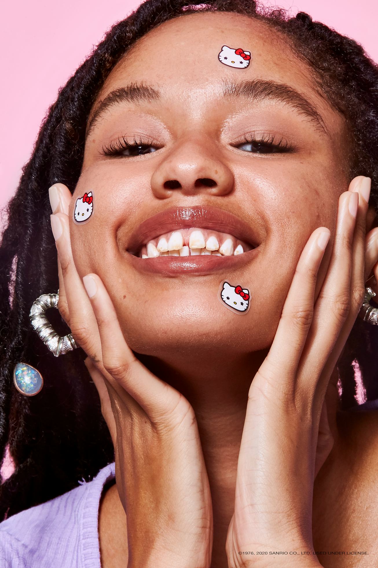 A person smiling with Starface x Hello Kitty stickers on their face