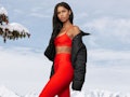 A young woman poses in red and black pieces from Alo Yoga against a wintery background.