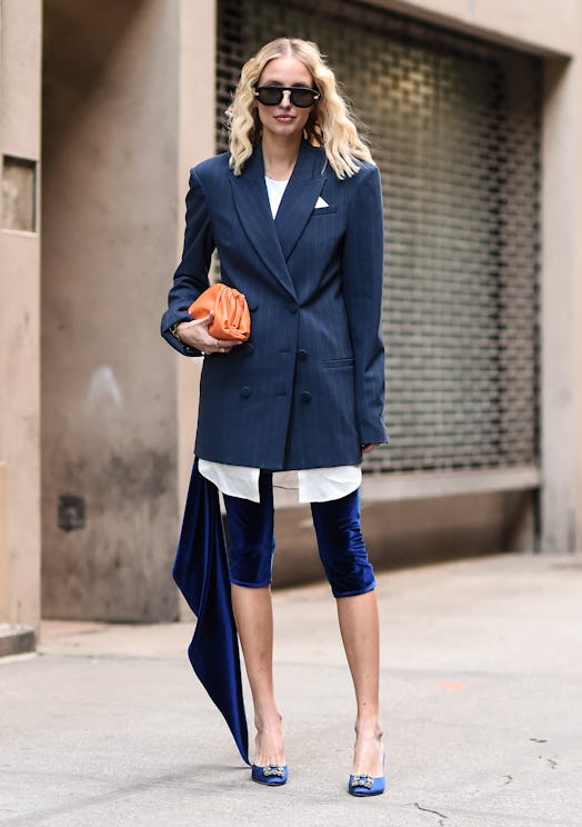 Leonie Hanne in a white shirt, navy blazer, navy short leggings and blue heels