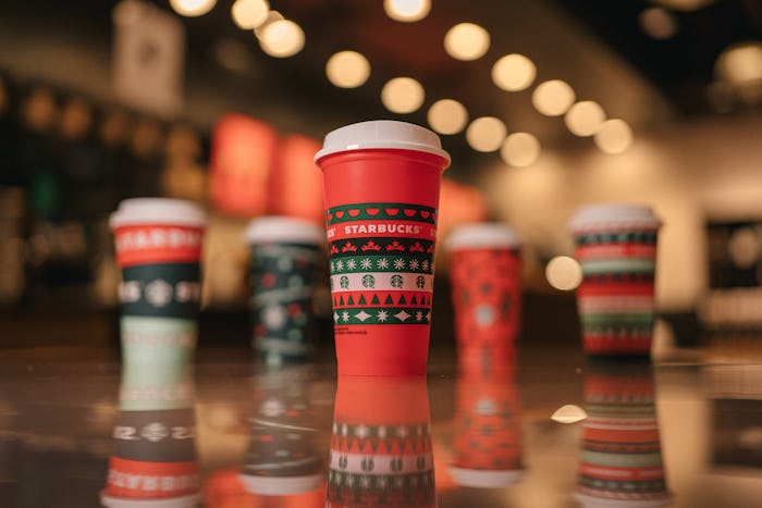 An image of a red Starbucks cups with Christmas trees and snowflakes on the exterior with four addit...