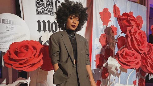 Young lady with curly hair posing in a dark green oversized suit