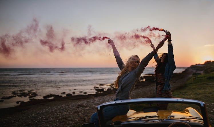 Hipster women having fun with smoke bombs at beach