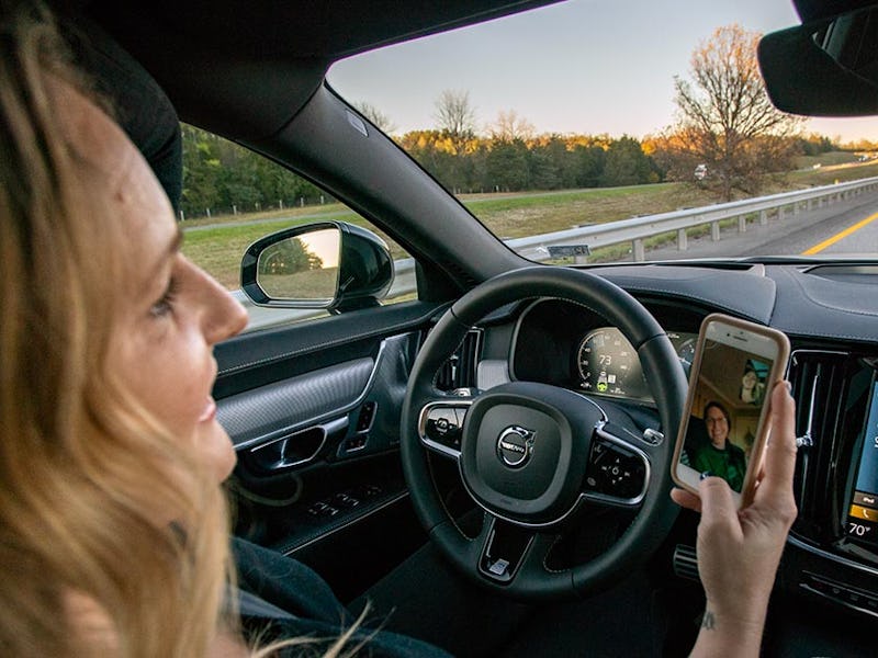 A person behind the wheel of a Volvo S90 Facetiming on their phone,