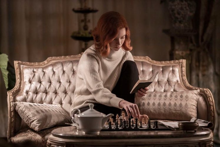 Beth Harmon (Anya Taylor-Joy) holds a chess book in her hand, while studying a game at home on her c...