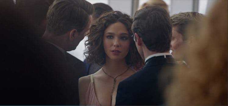 Elena from 'The Undoing' wears a light pink dress while chatting with a group of men at a fancy part...
