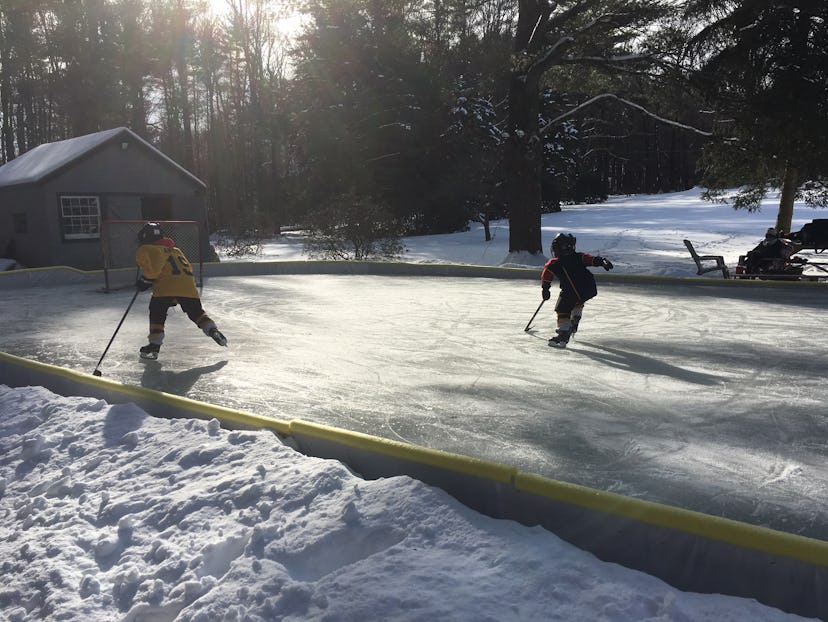 Kids play ice hokey on a backyard skate rink.