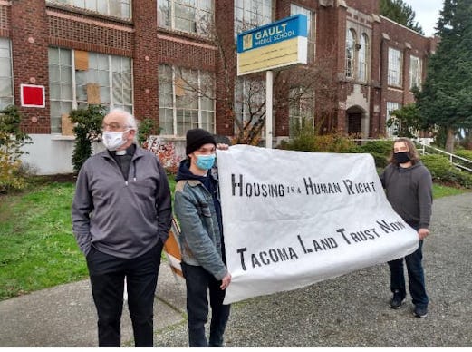 A group of housing activists in Washington holding a large poster in front of a vacant building