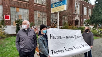 A group of housing activists in Washington holding a large poster in front of a vacant building