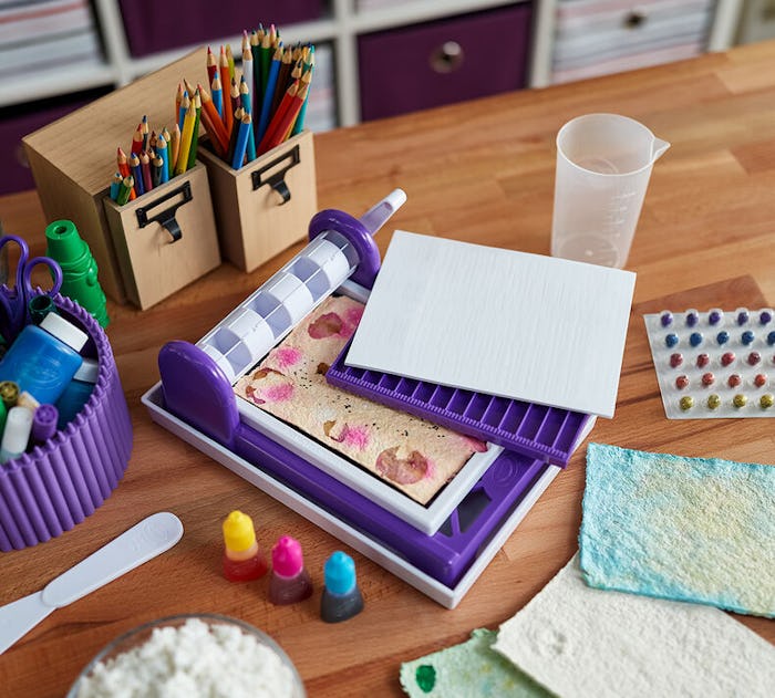 Crayola paper maker kit sitting on desk with colored pencils and craft supplies