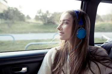 Young woman with windswept hair in a car wearing headphones