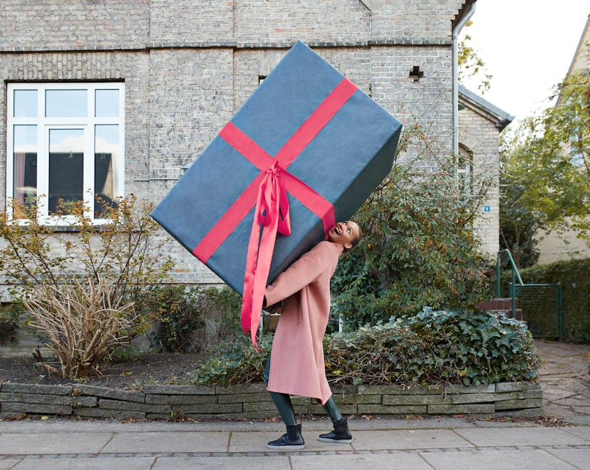 woman walking down the street carrying an oversized present