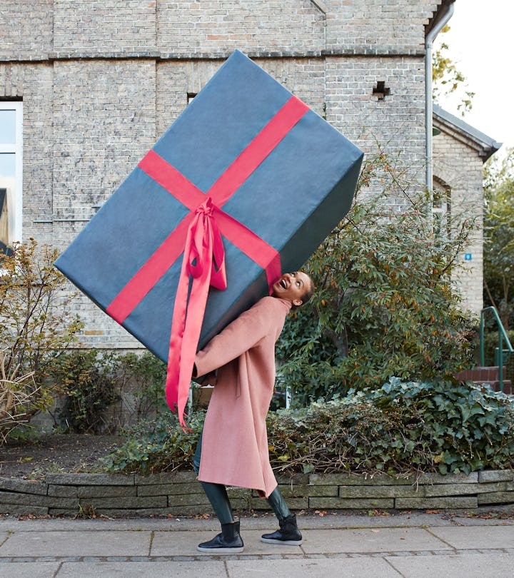 woman walking down the street carrying an oversized present
