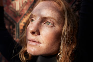 Woman looking away in sunlight against patterned wall