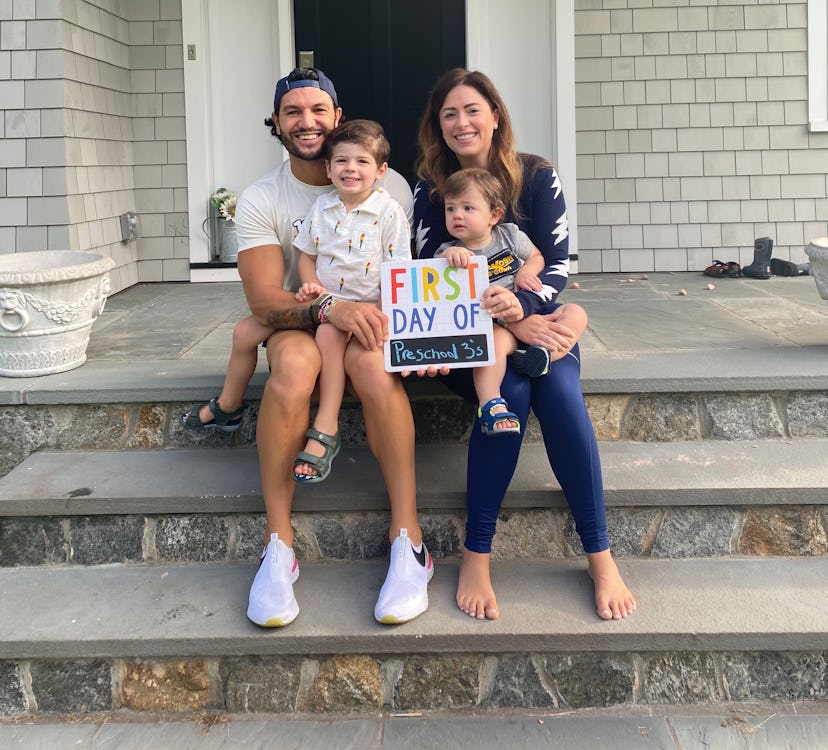 Brian Mazza sits on the front steps with his wife and their two little boys, holding up a "first day...