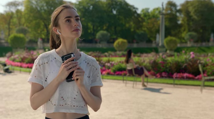 Emily (Lily Collins) stops to take a picture of a statue while going for a scenic run in Paris. 