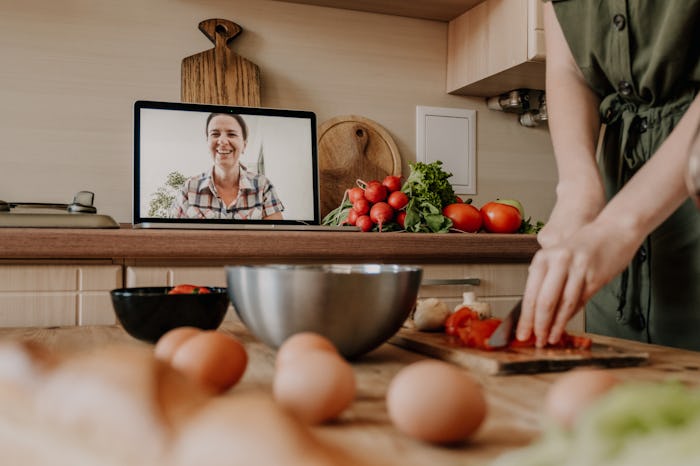woman cooking, chopping vegetables over video chat
