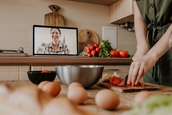 woman cooking, chopping vegetables over video chat 